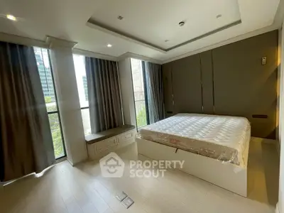 Spacious modern bedroom with large windows and elegant decor in a high-rise apartment.