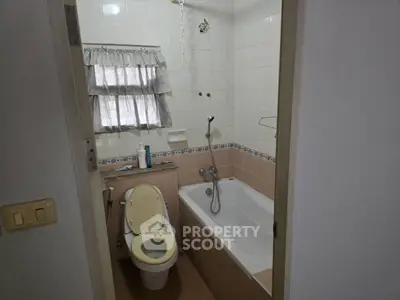 Cozy bathroom with bathtub and tiled walls, featuring a compact layout ideal for small spaces.