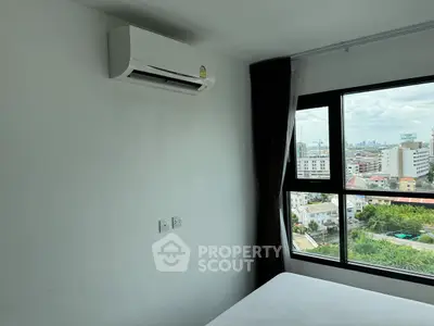 Modern bedroom with air conditioning and city view from large window.