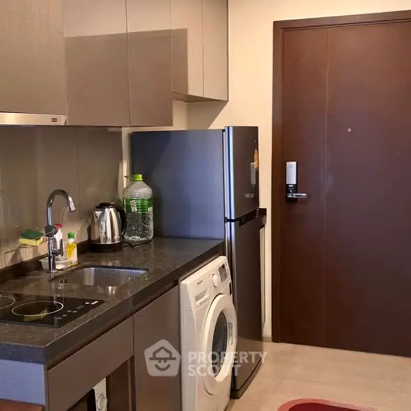 Modern kitchen with sleek appliances and washing machine in compact layout.