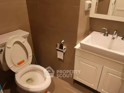 Modern bathroom with sleek fixtures and neutral tones, featuring a toilet and a stylish sink vanity.