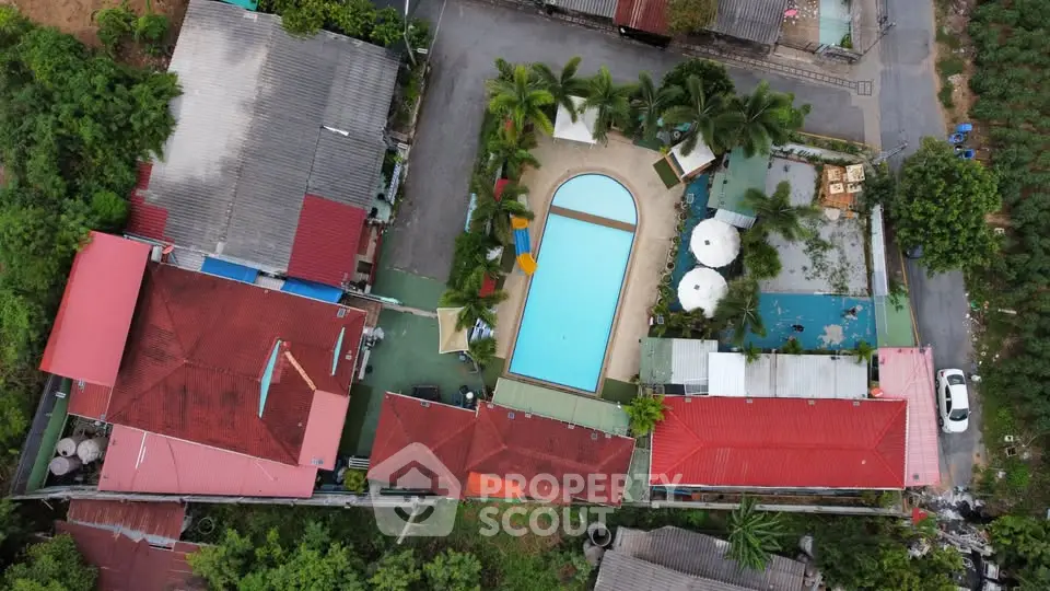 Aerial view of residential complex with central swimming pool and lush greenery.