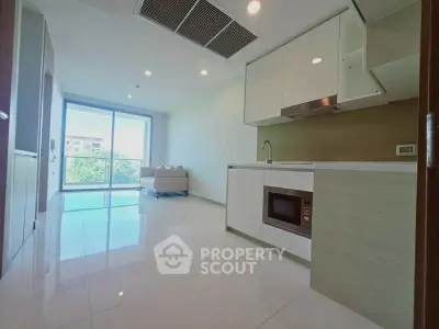 Modern open-layout kitchen with sleek design and spacious living area, featuring large windows for natural light.