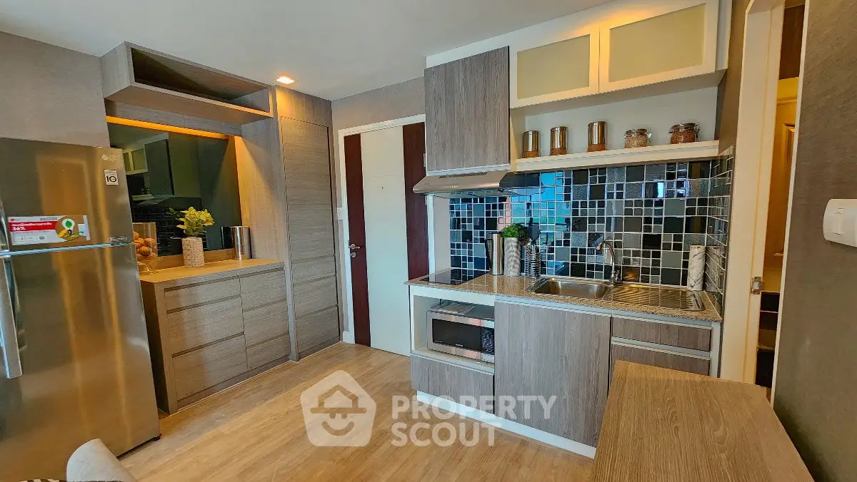 Modern kitchen with sleek cabinetry and stylish backsplash in a cozy apartment.