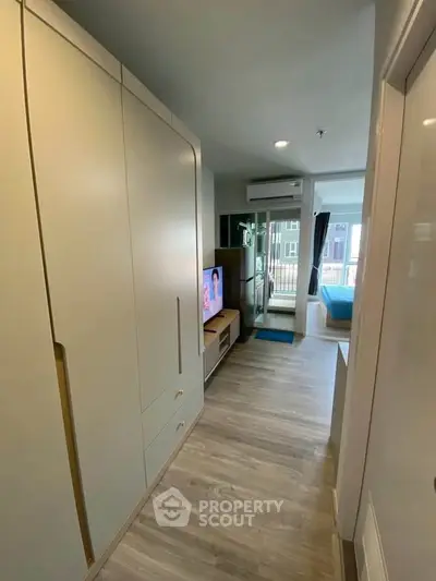 Modern apartment interior with sleek storage and cozy living area leading to a balcony.