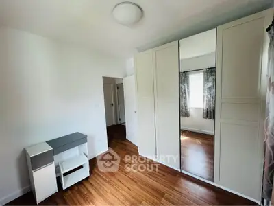 Spacious bedroom with wooden flooring and large mirrored wardrobe