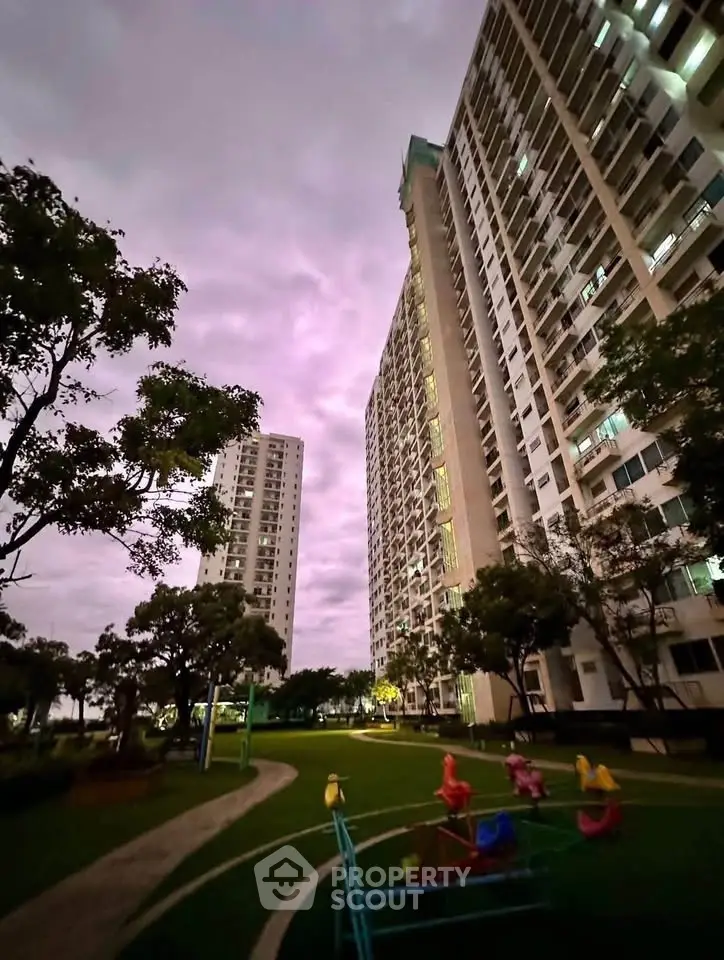 Stunning view of modern high-rise residential buildings with lush green garden at dusk.