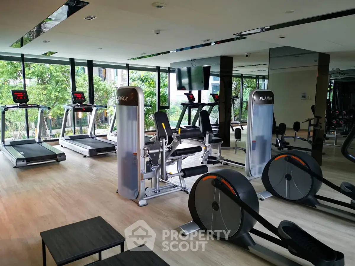 Modern gym with state-of-the-art equipment and large windows offering a lush green view.