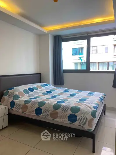 Modern bedroom with large window and stylish bedding in a contemporary apartment.