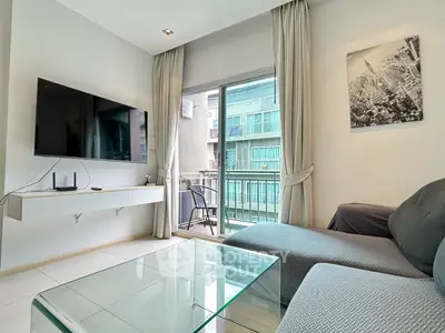 Modern living room with balcony view, featuring sleek furniture and wall-mounted TV in a stylish apartment.