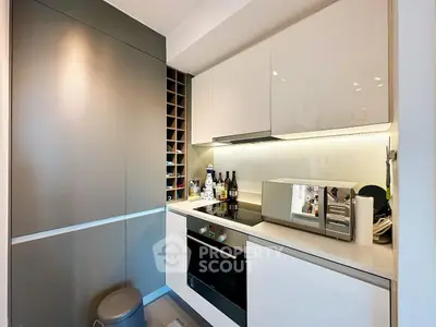Modern kitchen with sleek cabinetry and built-in oven, featuring a stylish wine rack.