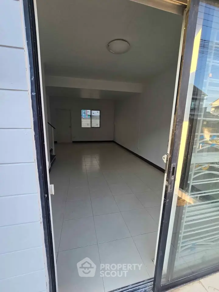 Spacious unfurnished room with tiled flooring and large window, perfect for customization.