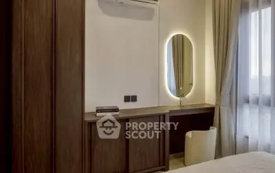 Elegant bedroom with modern vanity and ambient lighting, featuring a cozy chair and large window for natural light.