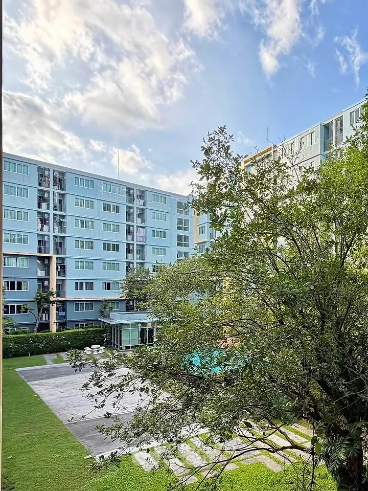 Modern apartment building with lush garden and clear blue sky view.
