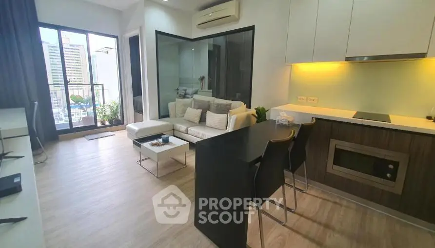 Modern open-layout living room with sleek kitchen and city view balcony in a high-rise apartment.