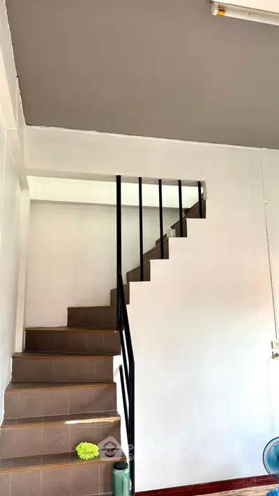 Modern staircase with sleek black railing in a minimalist interior setting.