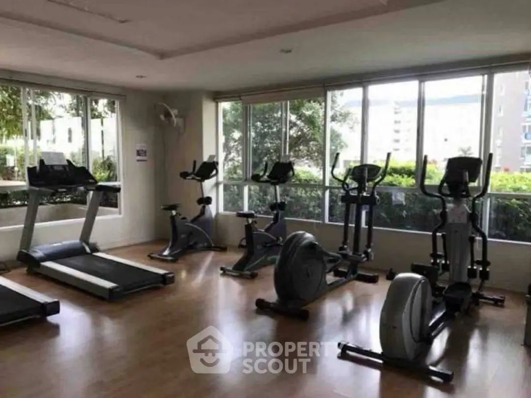 Modern gym with large windows and exercise equipment in a residential building.