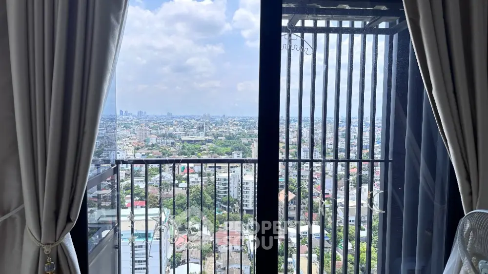 Stunning cityscape view from high-rise balcony with elegant curtains framing the skyline.