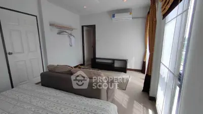 Bright bedroom with cozy sofa and air conditioning, featuring large windows and modern decor.