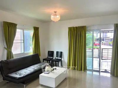 Spacious living room with modern sofa and elegant chandelier, featuring large windows and sliding glass doors.