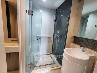 Modern bathroom with glass shower and sleek fixtures in contemporary apartment.