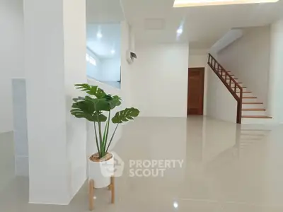 Spacious modern interior with sleek staircase and elegant plant decor, perfect for contemporary living.