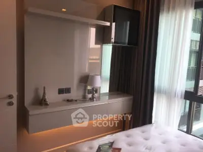 Modern bedroom with sleek furniture and large window offering natural light.