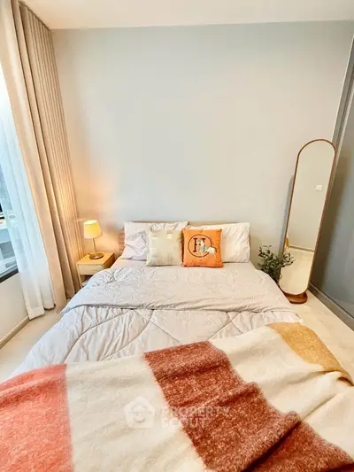 Cozy bedroom with stylish decor and natural light, featuring a comfortable bed and elegant floor mirror.