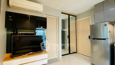 Modern apartment interior with sleek TV setup and stainless steel fridge