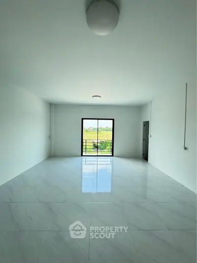 Spacious modern living room with large window and glossy tiled floor, offering ample natural light.