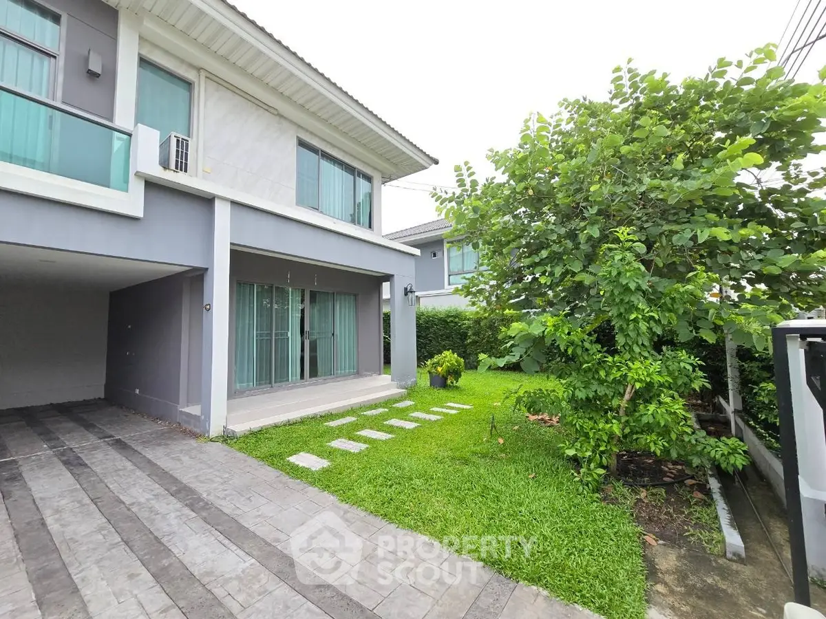 Modern two-story house with lush garden and driveway