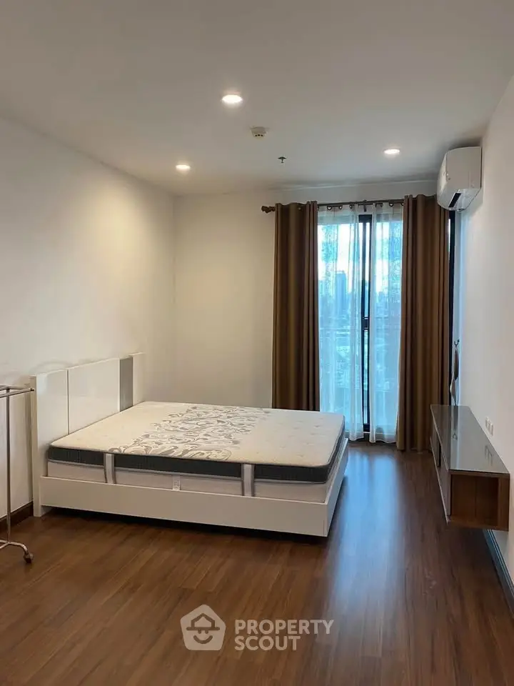 Spacious bedroom with modern furnishings and large window for natural light.