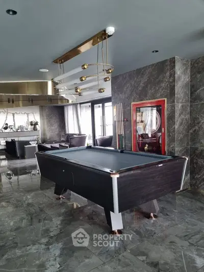 Luxurious living room with pool table and modern decor, featuring marble flooring and elegant lighting.