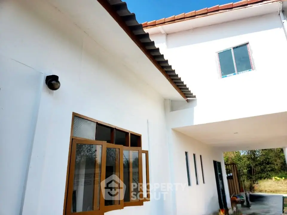 Charming white exterior of a modern home with open windows and a spacious driveway.