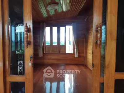 Charming wooden interior with polished floors and large windows offering natural light.