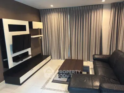 Modern living room with sleek black leather sofa and stylish entertainment unit.