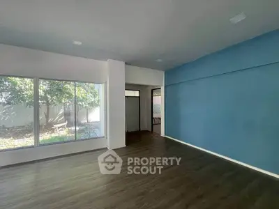Spacious living room with large windows and blue accent wall, offering natural light and garden view.