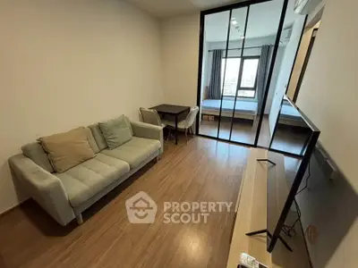 Modern apartment with cozy living room and bedroom separated by glass doors, featuring a sleek TV setup.