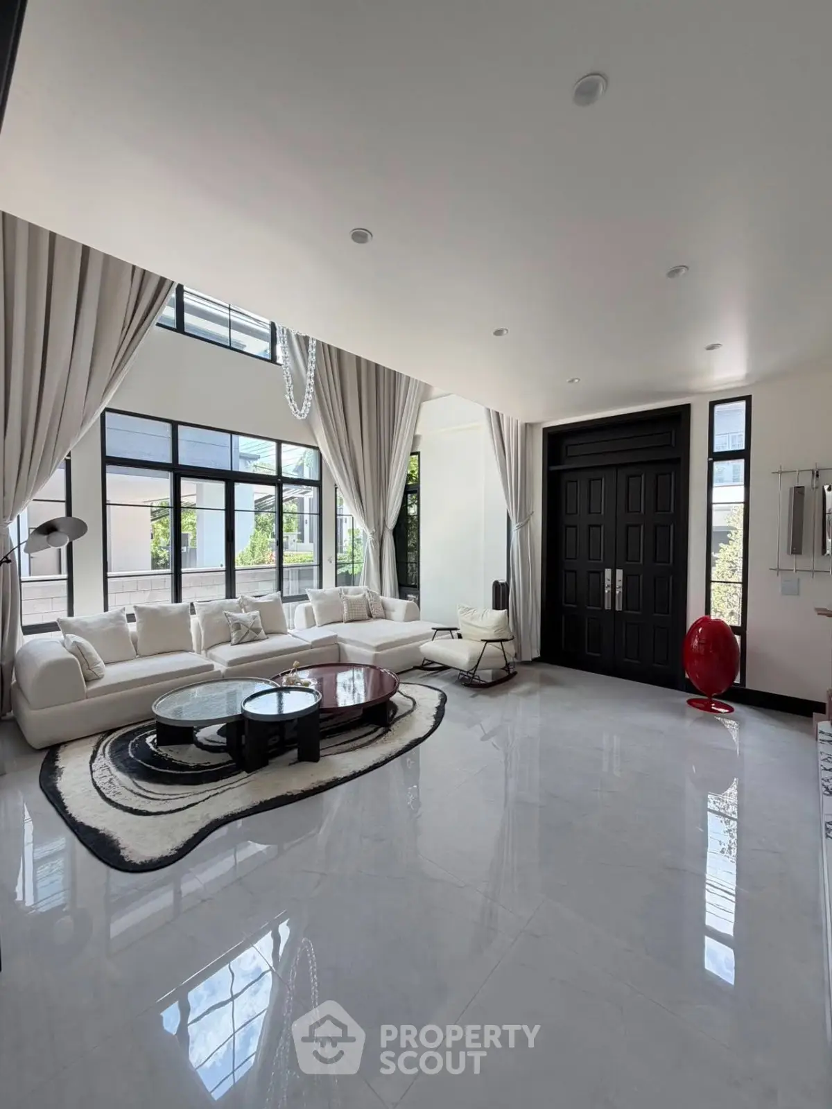 Luxurious modern living room with high ceilings, elegant decor, and large windows offering abundant natural light.