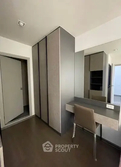 Modern bedroom with sleek wardrobe and stylish vanity in a contemporary apartment.