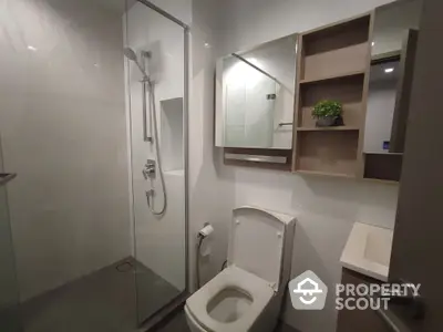 Modern bathroom with glass shower and sleek fixtures in contemporary apartment.