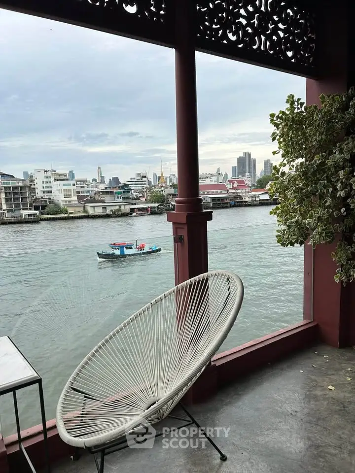 Stunning riverside view from a balcony with modern chair and cityscape backdrop.
