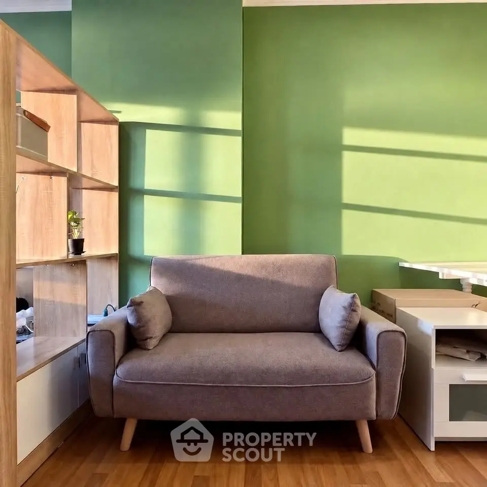 Cozy living room with modern sofa and stylish shelving unit against a vibrant green wall.