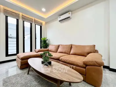 Modern living room with stylish brown leather sofa and sleek coffee table, featuring large windows and elegant decor.