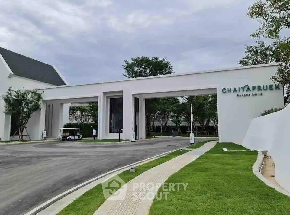 Elegant entrance of Chaiyapruk housing estate with lush greenery and modern architecture.