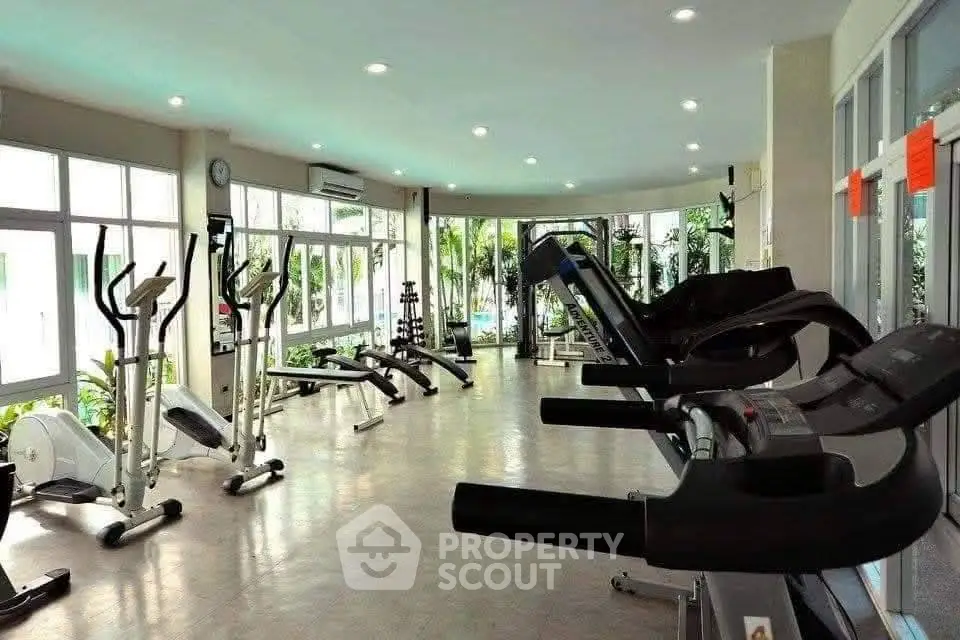 Spacious gym with modern equipment and large windows offering garden views.