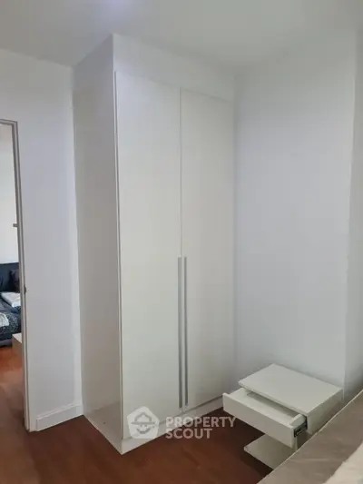 Modern bedroom with sleek white wardrobe and wooden flooring