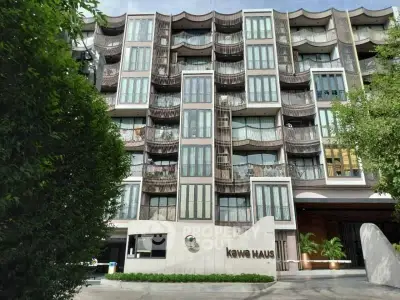 Modern multi-story residential building with unique balcony design and lush greenery.