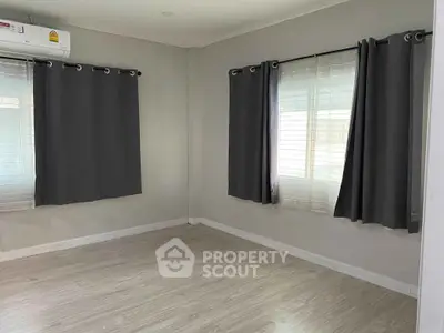 Spacious empty room with large windows and modern curtains