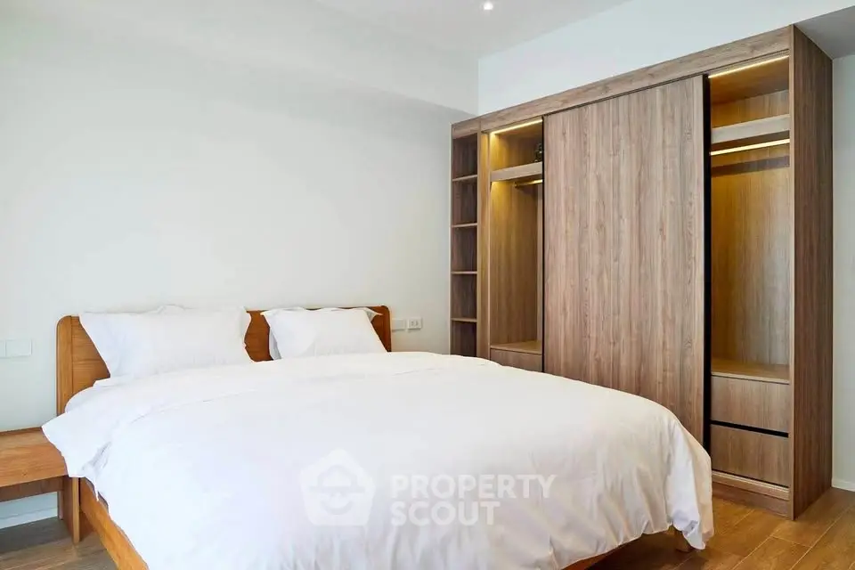 Modern bedroom with wooden wardrobe and cozy white bedding